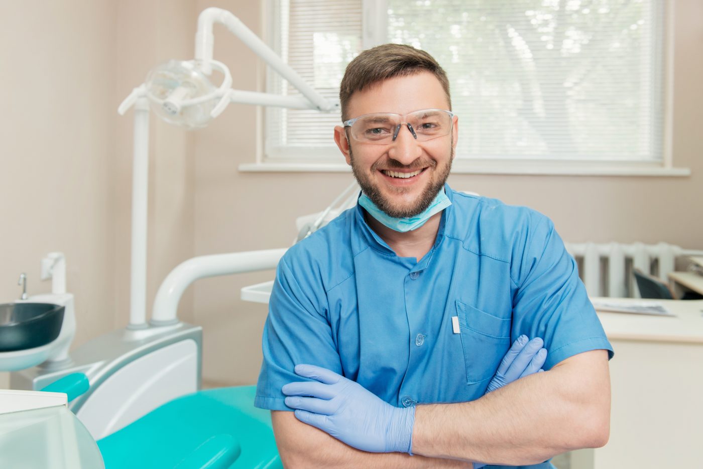 Portrait of friendly dentist in the dental office with folded hands